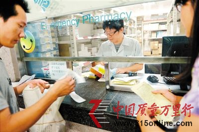 　7月1日零時20分，在市人民醫(yī)院取藥窗口，就診的患者查看處方和藥費單。 深圳商報記者 薛云麾 攝